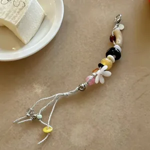 Detailed view of handmade beaded phone charm featuring colorful floral pendants and metal details.