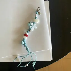 Detail view of handmade beaded phone charm with blue cord, white flower and colorful beads.