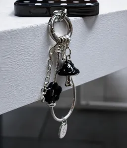 Close-up detail of the edgy metallic snake chain mushroom phone charm with black floral pendants.