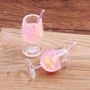 Nahaufnahme des Miniatur-Harz-Cocktailglas-Anhängers, rosa Flüssigkeit mit Zitrone und Strohhalm.