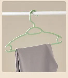 Green plastic clothes hanger featuring non-slip design and grey pants, clear detail shot.