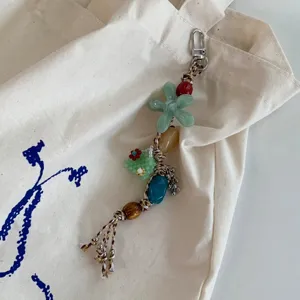 Detailed view of handmade beaded braided phone charm and bag pendant with green floral design.