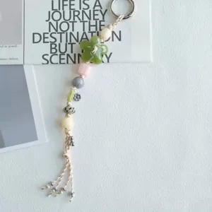 Closeup detail view of summer beaded phone charm featuring green flower and mixed beads.