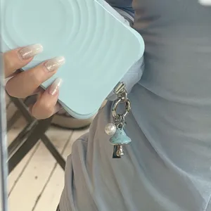 Exquisite blue mushroom pearl phone charm close-up, retro enamel accessory for stylish look.