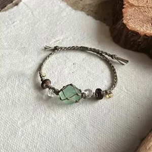 Handgeweven macramé armband met omwikkelde groene kristalsteen en kralen in detail