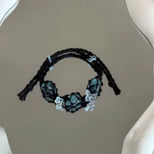 Detailopname van de prachtige handgemaakte zwarte macramé armband met unieke blauwe stenen.