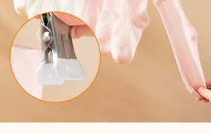 Detalle de pinza de acero inoxidable con puntas protectoras blancas para calcetines.