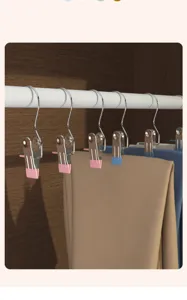 Vista detallada de pinzas metálicas colgando de una barra, sujetando los pantalones firmemente.