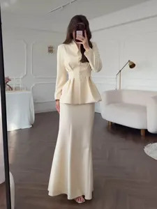 Elegant beige two-piece skirt set with long sleeve peplum top and maxi skirt for women.