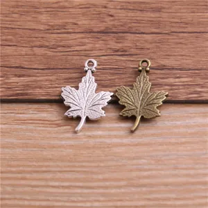 Close-up detail of silver and bronze maple leaf charms, perfect for DIY jewelry making.