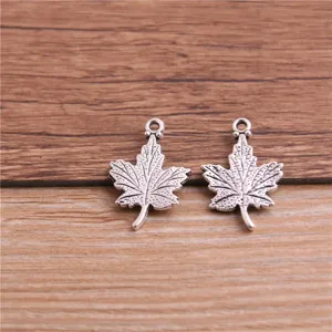 Detailed close-up of silver-tone maple leaf metal charms, perfect for DIY jewelry making.