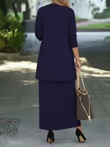 Outdoor detail view of a solid navy blue long-sleeve jacket and maxi skirt outfit style.