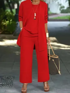 Detail view of a stylish red three-piece women pantsuit featuring open cardigan and trousers.
