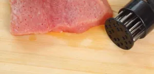 Strumento batticarne professionale in acciaio inossidabile con aghi per carne.