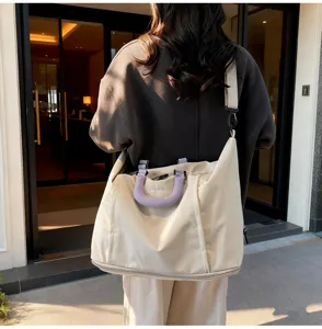 Vue détaillée du grand sac de voyage beige avec poignée violette et bandoulière pratique.