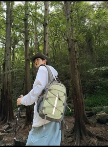 Detailed view of hiking backpack in forest, featuring green and grey color blocking.