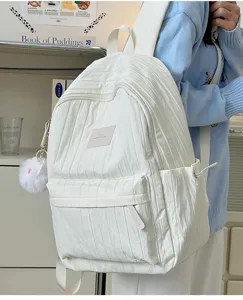 Vue détaillée du sac à dos plissé blanc porté par le modèle, montrant texture et bretelles.