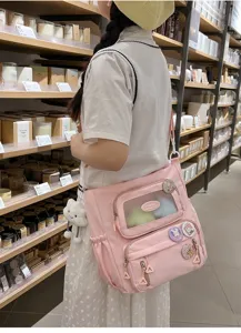 Nahansicht der süßen rosa Ita-Tasche mit transparentem Sichtfenster, Pins und Wolkenanhänger.