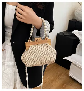 Detailaufnahme der geflochtenen Handtasche mit Holzverschluss und Perlenkette im Sommer.