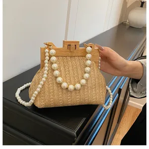 Nahaufnahme der Strohhandtasche mit Holzrahmen und elegantem Perlenschulterriemen.