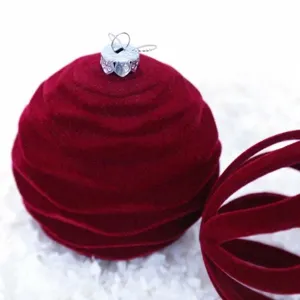 Primer plano bola de navidad de terciopelo burdeos, textura flocada suave, adorno festivo.