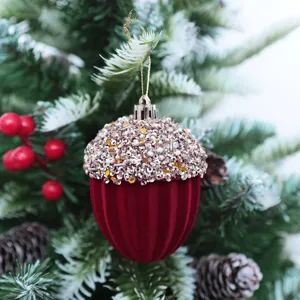 Primer plano de un adorno navideño de bellota de terciopelo burdeos con detalles de lentejuelas.
