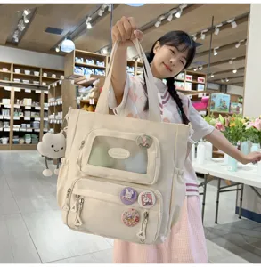 Canvas Shopper Ita Bag mit durchsichtiger Fronttasche, süßen Ansteckern und Anhänger.
