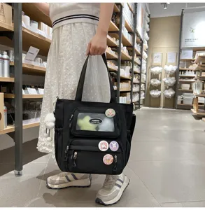 Schwarze Canvas Ita Tasche mit transparentem Fenster und süßen Hasen-Ansteckern für den Alltag.