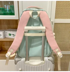 Detailansicht des pastellrosa und blauen Colorblock Studentenrucksacks mit Kofferband.