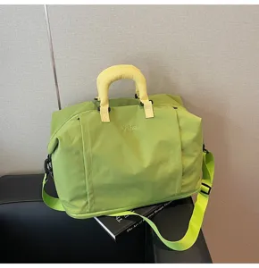 Vue détaillée du grand sac de voyage souple en vert clair avec une jolie poignée jaune.