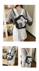 Detailed view of black star Ita bag featuring clear window and cute anime badges worn on back.