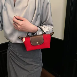 Kleine rote Nylon Handtasche mit brauner Lederlasche, elegantes Design für den Alltag.
