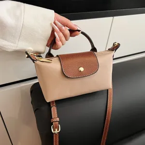 Detailansicht der kleinen Handtasche mit brauner Klappe und eleganten goldenen Beschlägen.