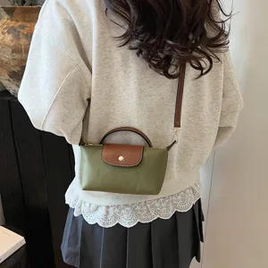 Detailansicht der kleinen Nylon Umhängetasche mit grünem Körper und brauner Lederklappe.