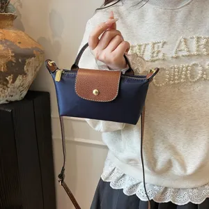 Detailansicht der Mini-Nylon-Tasche mit brauner Lederklappe und praktischem Umhängeriemen.