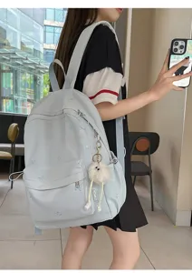 Detailansicht des hellblauen Rucksacks mit Schleifenstickerei und Plüschanhänger am Modell.