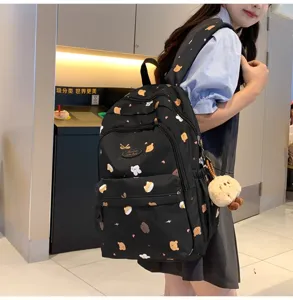 Detailansicht des kleinen schwarzen Rucksacks mit Bärenmuster und Plüschtier-Anhänger.