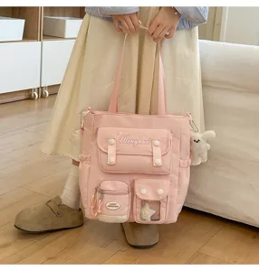 Detailansicht der rosa Canvas-Tragetasche mit mehreren Fronttaschen und süßem Abzeichen.
