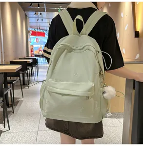 Detailansicht des frischen hellgrünen Rucksacks mit süßen bestickten Schleifenmuster und Anhänger.