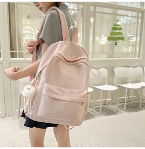 Detailansicht des niedlichen rosa Studentenrucksacks mit zarter Schleifenstickerei und Plüsch.
