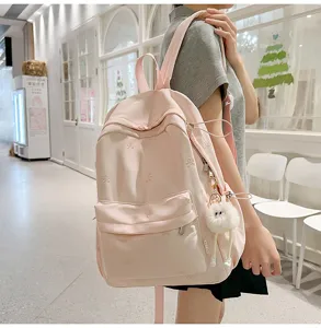 Detailansicht des niedlichen rosa Rucksacks mit Schleifenstickerei und Plüschanhänger.