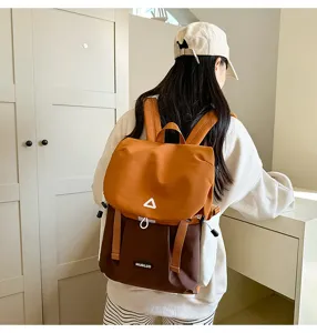Backpack detail view showcasing orange and brown color block design with shoulder straps.