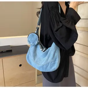 Close-up detail of the light blue denim hobo bag featuring a matching round pouch.