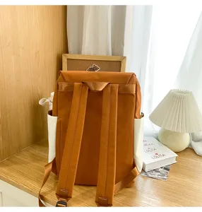 Detail view of a casual outdoor backpack in brown with white side pockets, placed on a desk.
