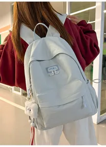 Detailansicht des lässigen hellblauen Rucksacks mit süßem Plüschanhänger und stylischem Patch.