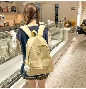 Detailansicht des lässigen gelben Rucksacks mit Fronttasche und niedlichem Anhänger.