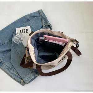 Grosse beige Segeltuchtasche mit braunen Riemen, detaillierte Innenansicht fur Studenten.