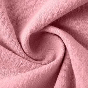 Close-up detail of soft pink cotton linen fabric texture, breathable summer material.