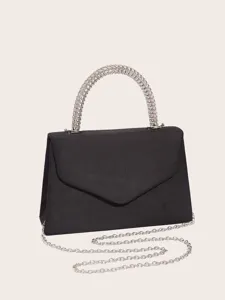 Detail shot of black velvet evening bag featuring structured metal handle and silver chain strap.