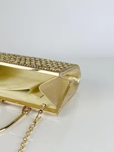 Nahaufnahme einer glamourösen goldenen Strass-Abendtasche mit Metallrahmen und Kette.